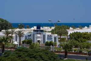 沙姆沙伊赫玛丽蒂姆沙姆沙伊赫赌场度假酒店的一座白色的建筑,在海洋前方种有棕榈树