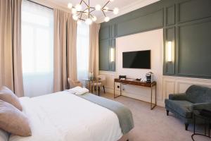 波尔多Maison Heym Bordeaux的一间卧室配有一张床、一张书桌和一台电视。