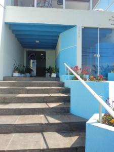 巴拉那州蓬塔尔HOTEL PORTO FINO的蓝白色的建筑,有楼梯和植物