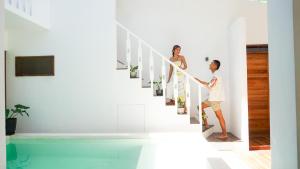 爱妮岛Lugadia Villas的两对夫妇在带游泳池的房子里走下楼梯