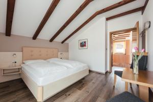 梅拉诺Hotel Garni Sirmian的卧室配有白色的床和桌子