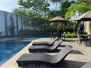 雅加达2 Floor Cozy House in Wisteria Jakarta Garden City的游泳池配有桌椅和带雨伞的桌子