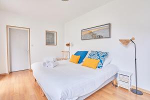 迪纳尔Ker Lys - Grande maison avec 4 chambres et jardin的一间卧室配有白色的床和蓝色和黄色枕头