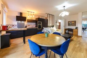 雷恩Le Saint Cyr - bel appartement, parking & terrasse的厨房以及带桌子和蓝色椅子的客厅。