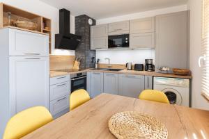 迪纳尔Le Magellan - logement neuf, parking, grand balcon的厨房配有木桌和黄色椅子