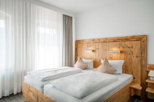 施塔特韦伦Manufaktur Boutique Hotel的一间卧室配有两张白色的床和木制床头板