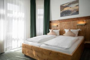 施塔特韦伦Manufaktur Boutique Hotel的一间卧室配有一张带白色床单和枕头的木制床。