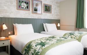 罗克瑟姆The Kings Head Wroxham by Greene King Inns的配有绿窗帘的酒店客房的两张床