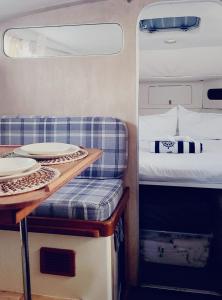 巴塞罗那Cosy and Homey Houseboat Castelldefels的一间房间,配有床和一张桌子,上面有盘子