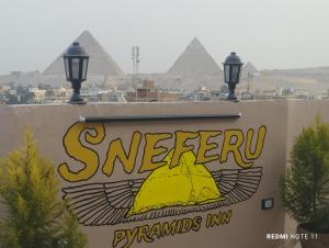 开罗Sneferu Pyramids inn - Full Pyramids View的背景中带有金字塔的标志