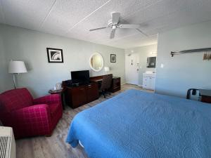 波因特普莱森特海滩Sand Pebble Motor Lodge的一间卧室配有蓝色的床和红色椅子