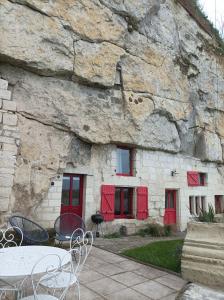 蒙索罗Gite des Perreyeurs - maison troglodyte avec vue sur Loire的石头建筑,有红色的门和桌子