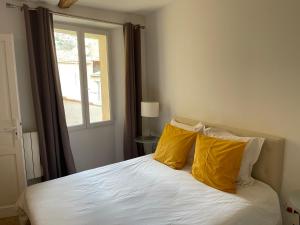 穆斯捷-圣玛丽La Maison du Courtil, Amande-Olive的一间卧室配有一张带黄色枕头的床和一扇窗户