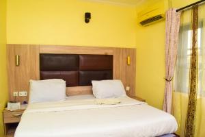 Ijesa-TedoLisgewann Global Hotel的一张大床,位于拥有黄色墙壁的房间