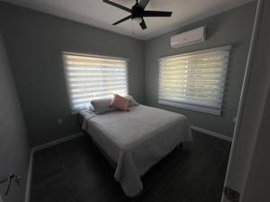 乌蒂拉Baquis Island Bungalow的一间卧室配有一张带风扇的床和两个窗户。