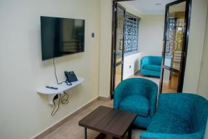 埃尔多雷特The Kolel Hotel and Suites的一间设有两把椅子、一台电视和一张桌子的房间