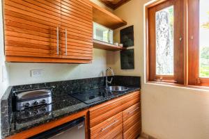 蓬塔卡纳Newly added Tropical Bungalow at Green Village的厨房配有木制橱柜、水槽和炉灶。