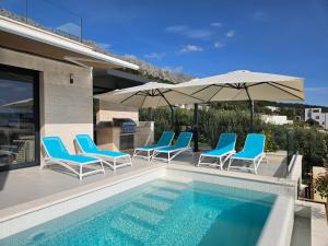 耶塞尼采Villa Askana, 3 Bedrooms, 4 Baths, Infinity Pool, Whirlpool, Sea view, Outdoor kitchen的一个带蓝色椅子和遮阳伞的游泳池