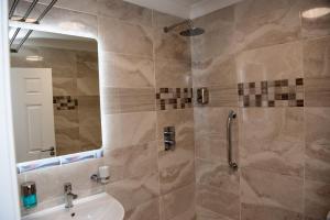多尼戈尔Donegal House的浴室配有盥洗盆和带镜子的淋浴