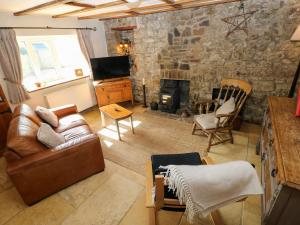 纳伯斯1 Mill Farm Cottages的带沙发和石墙的客厅