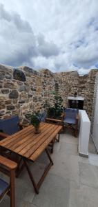PyrgiSKINOS rooms and apartment的庭院设有木桌、椅子和石墙