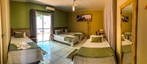 波科内Pousada Rio Claro的一间设有两张床铺的客房,位于带绿色墙壁的房间内