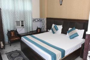 新德里Hotel Royal Inn的一间卧室配有一张带蓝白色枕头的大床