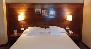 拉瓦克拉圣雅各之路酒店的一间卧室配有一张带两盏灯的床和一部电话