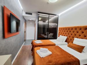 布德瓦Lolo Luxury rooms & suites的酒店客房设有两张床和电视。