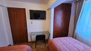库斯科Los Profesionales - Hospedaje的一间卧室配有一张床、一张书桌和一台电视。