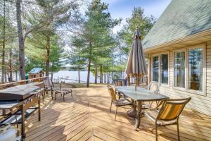 NeillsvilleLakefront Neillsville Home with Fire Pit, Game Room!的一个带桌椅的甲板和一把遮阳伞
