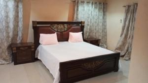 索蒙Al jannah Bis的卧室配有一张带白色床单和粉红色枕头的大床。