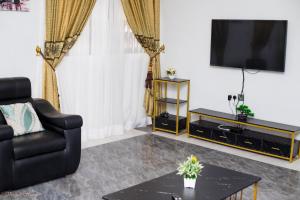 库马西Stunning Executive 2 Bedroom Apartment with KING SIZE BED的客厅配有黑椅和电视