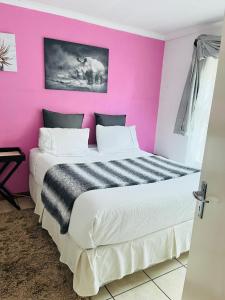 肯普顿帕克Private Holiday home in Kempton park的粉红色墙壁的房间里一张床位