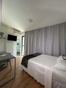 大坎皮纳Hotel do Vale的卧室配有白色的床、桌子和窗户。