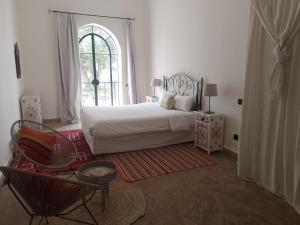 GhazouaDomaine de l'Arganeraie的卧室配有床、椅子和窗户。
