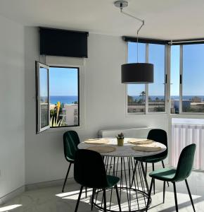 莫罗德哈布雷Jandia Beach Apartment 2的一间带桌子和绿色椅子的用餐室