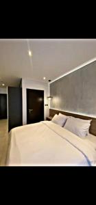 阿克拉The Signature Hotel Apartment Accra Ghana的卧室配有一张白色大床和灰色床头板