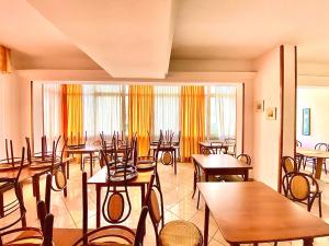 里米尼Hotel Majorca Nuova Gestione Rimini 100 m dalla spiaggia的餐厅设有木桌、椅子和窗户。