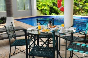 坎昆亲密套房酒店的一张桌子,上面有盘子的食物,放在游泳池边