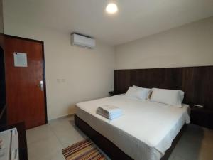 San Juan del ParanáHotel Villa的卧室配有一张白色大床和木制床头板