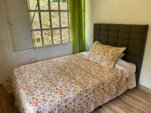 SamanáCasa Kakawa Ecolodge的一间卧室配有一张带花卉棉被的床和窗户。