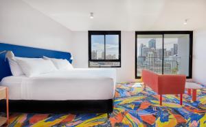 悉尼Adge Hotel and Residences的卧室配有白色的床和红色椅子