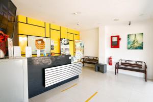 怡保Golden Roof Hotel Sunway Ipoh的商店大厅设有两把长椅和黄色及白色的墙壁