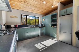 箭镇Maytime Cottage - Arrowtown Holiday Home的厨房设有绿色的橱柜和木制天花板。