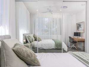 黄金海岸Luxury Mermaid Waters Holiday Home的一间白色卧室,配有两张床和一张书桌