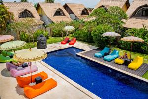 坎古巴厘岛颜色联合酒店的游泳池旁设有五颜六色的椅子和遮阳伞