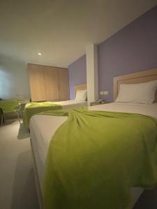 卡塔赫纳Hotel Isla Capri的配有两张绿色和白色床单的床铺