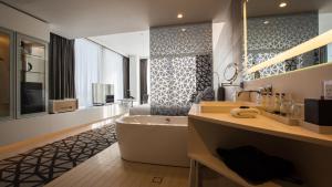 悉尼悉尼机场铂尔曼酒店的带浴缸和盥洗盆的浴室以及电视。