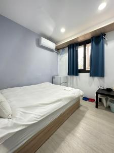 台中市FunSong逢甲的卧室配有一张带蓝色窗帘的大型白色床